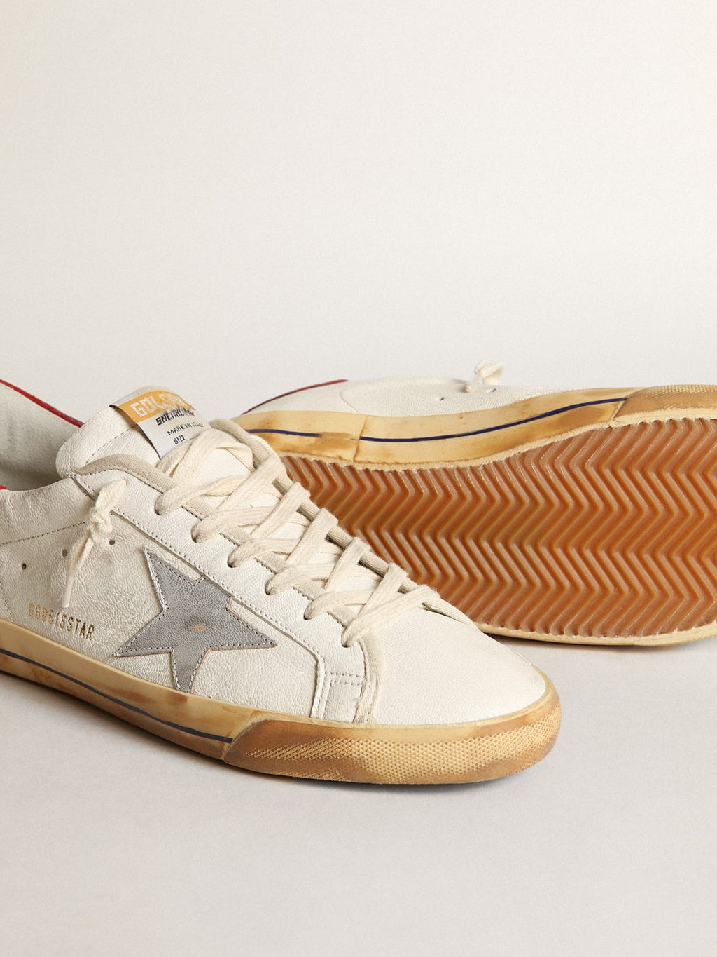 Sneaker Super-Star con stella in pelle laminata color argento e talloncino in suede rosso